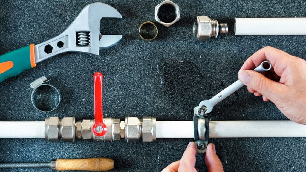 Plumber repairing a pipe valve with an adjustable wrench in Stuart