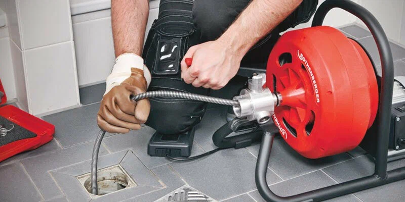 Plumber using a drain-cleaning machine in Stuart