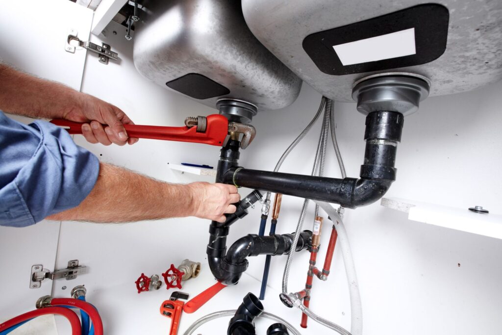 Plumber repairing drain pipes beneath a kitchen sink in Stuart