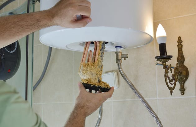 Technician removing mineral buildup from a water heater in Stuart